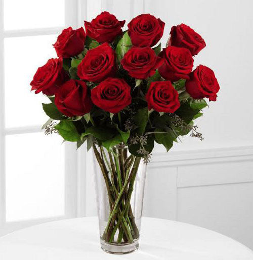 Dozen fancy red roses arranged in a glass vase