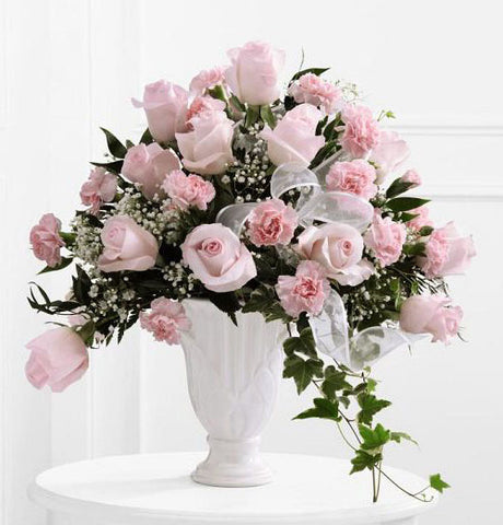 Deepest sympathy funeral flower arrangement of pink roses in a white urn