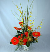 Enticing exotics tropical flower arrangement of oranges and yellows in silver vase