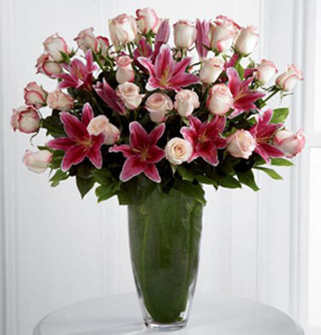 Exquisite luxury vase arrangement of roses and pink lilies in premium green vase