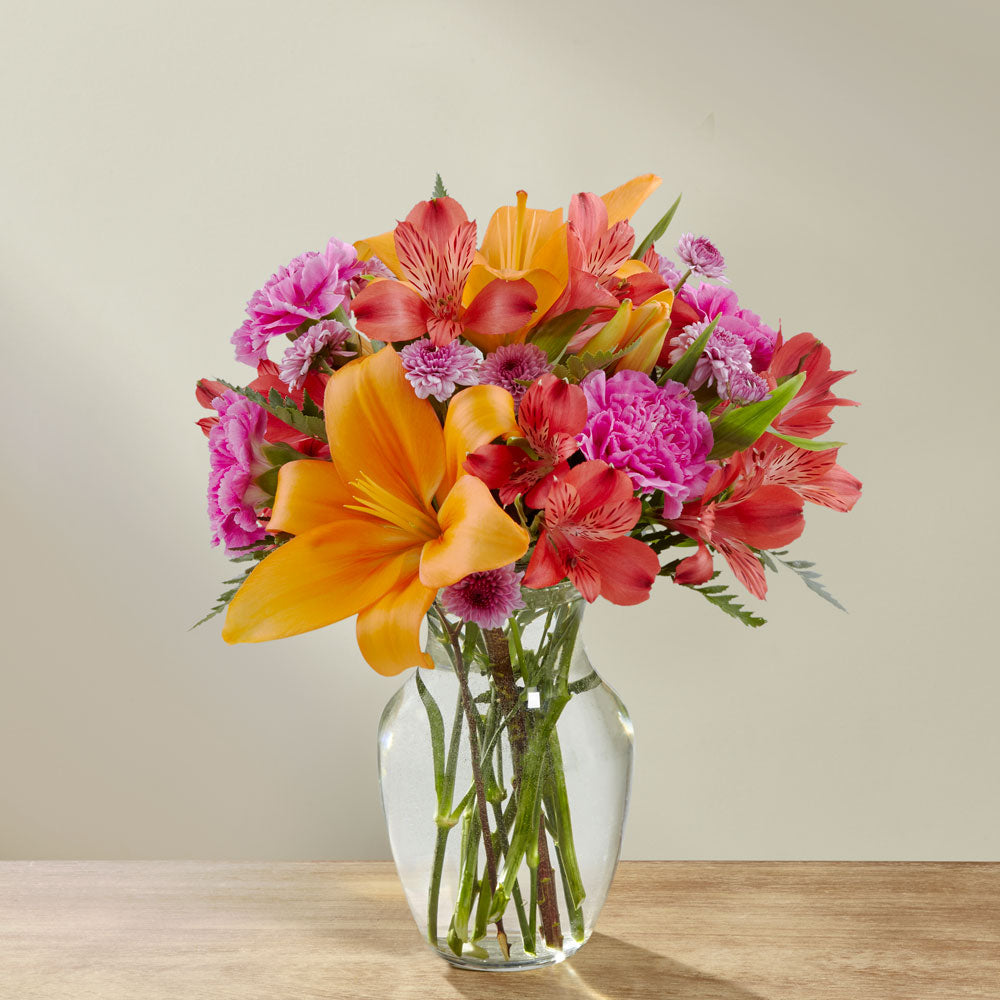 Orange lilies and hot pink mini carns in a glass vase Standard