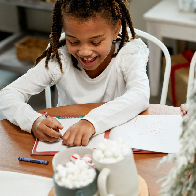 Child writing in Santa's Kindness journal