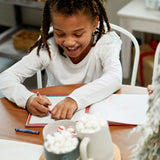 Child writing in Santa's Kindness journal